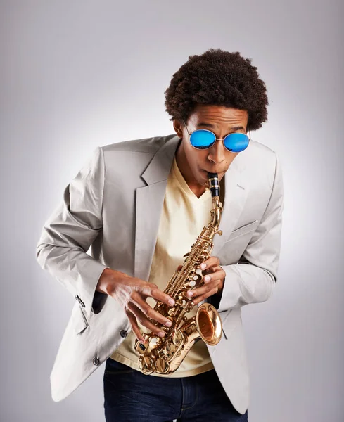 Lets talk about sax. Studio shot of a fashionable young man playing the saxophone