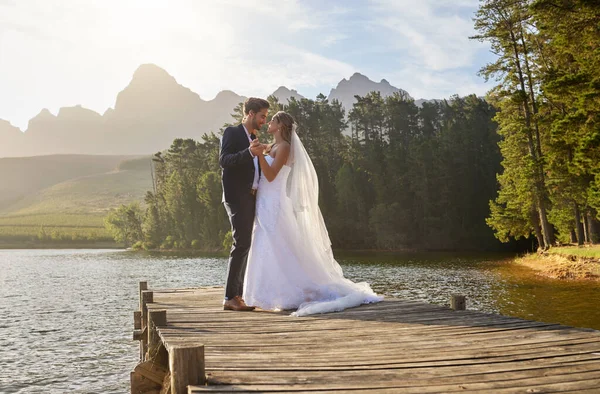 Love, dance and a married couple on a pier over a lake in nature with a forest in the background after a ceremony. Wedding, romance or water with a bride and groom in celebration of marriage outdoor.
