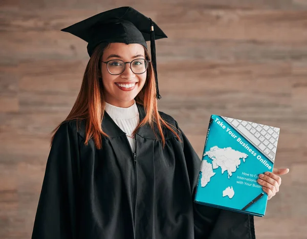 College graduation, woman and portrait with business textbook of a young student happy. Learning book, happiness and excited female ready for university education with a smile from knowledge.