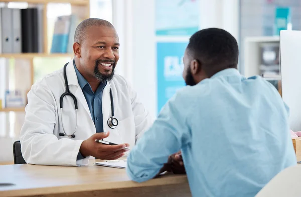 Happy, talking and doctor with a black man for healthcare, support and advice on treatment. Smile, consulting and an African gp with a patient speaking about medicine, health and professional help.