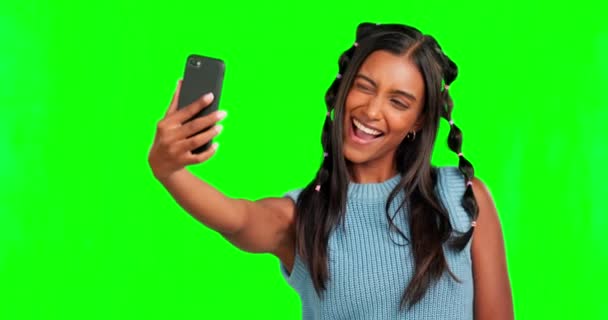 スタジオの背景に隔離された緑のスクリーンに 自撮り 舌を持つ少女 面白いと影響力のある女性が手のジェスチャーと愚かな顔の表情で写真を撮る — ストック動画