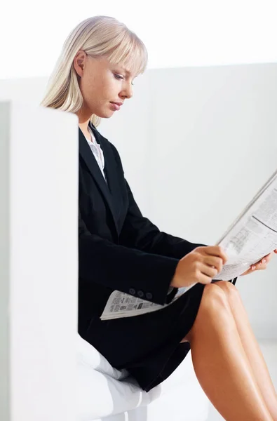 Business woman reading news. Side view of young business woman reading newspaper