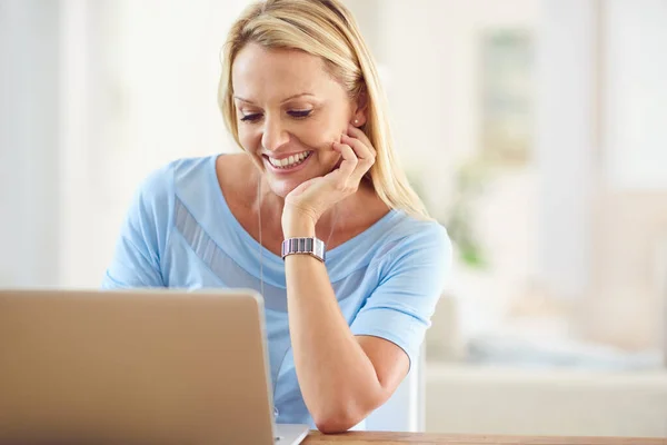 stock image I need to update my blog. an attractive mature woman sitting and using a laptop while in her living room during the day
