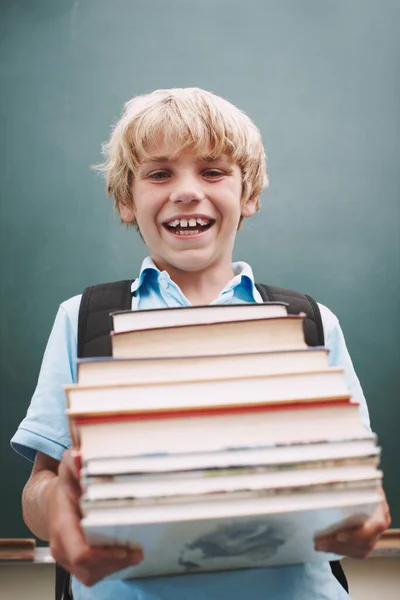 学ぶことに興奮してた 本の背の高いスタックを持っているとあなたに笑みを浮かべて熱心な若い学生 — ストック写真
