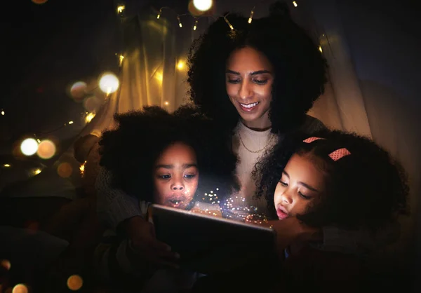 Tablet, night a mother reading to her kids in a tent while camping in the bedroom of their home together. Black family, story or children with a woman storytelling to her kids at bedtime for bonding.