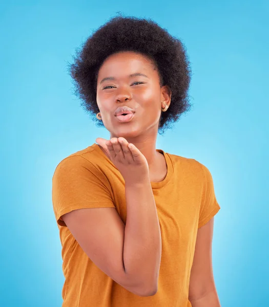 Portrait, black woman and blowing kiss on blue background of love, care and flirting in studio, color backdrop and face. Happy female model, hand kisses and emotion of happiness, fun or kissing emoji.