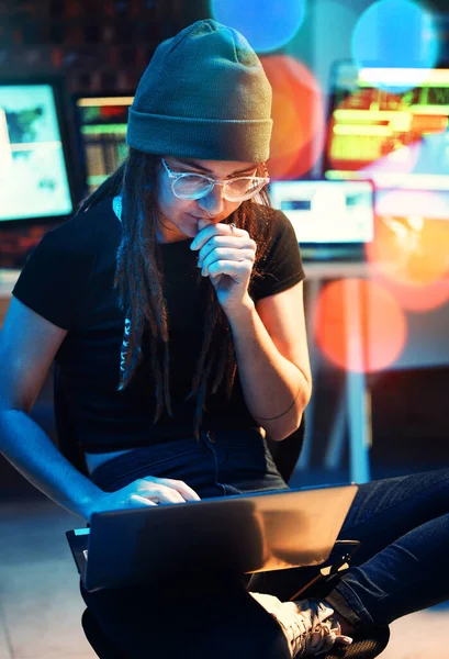 Woman, laptop and hacker thinking, typing or programming, software or cybersecurity. Neon, computer and it coder or programmer reading information for hacking idea while on dark web at night in home