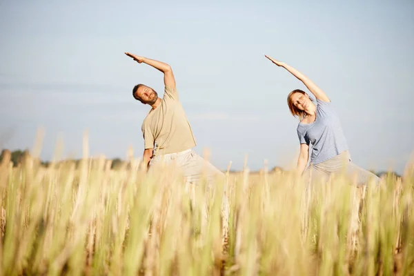 In perfect harmony. a mature couple enjoying a yoga workout in a crop field