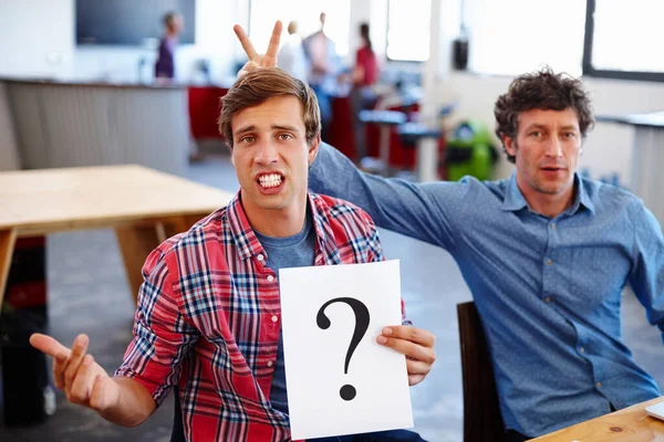 Searching for answers. Portrait of two coworkers looking confused while holding a question mark sign