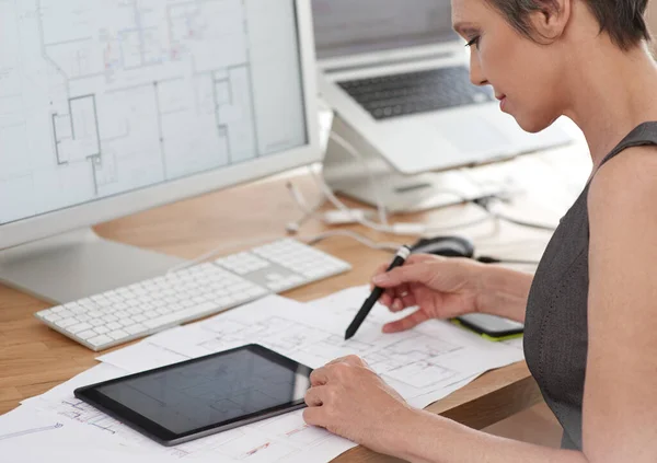 stock image Making the planning process more efficient. A mature female architect working on building plans using her digital tablet