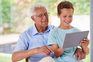 Teknolojiyi birlikte öğreniyoruz. Büyükbabasıyla dijital tablet kullanan bir çocuk.
