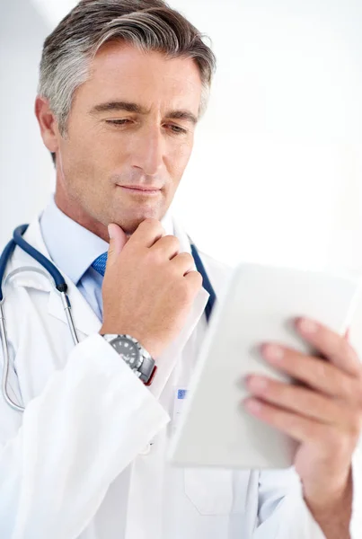 stock image Considering his treatment options. a doctor holding a digital tablet while standing in a hospital corridor