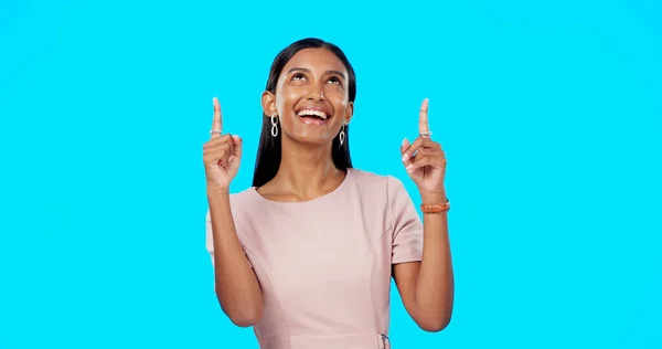 Face, pointing and Indian woman with direction, motivation and cheerful against a blue studio background. Portrait, female and lady with gesture for choice, direction and brand development with smile.