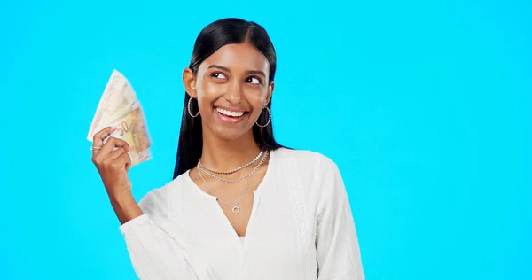 Rich, happy and face of a woman with money isolated on a blue background in a studio. Smile, wealth and a portrait of a girl fanning with cash, lottery jackpot and dollars from a bonus on a backdrop.