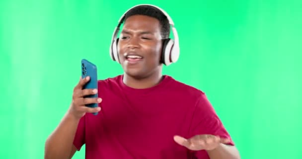 スタジオで踊る音楽ヘッドフォン 緑の画面 黒人男性が背景に隔離されています アフリカ人の携帯電話 歌と幸福をストリーミングし ポッドキャスト ラジオやオーディオを聞いて — ストック動画