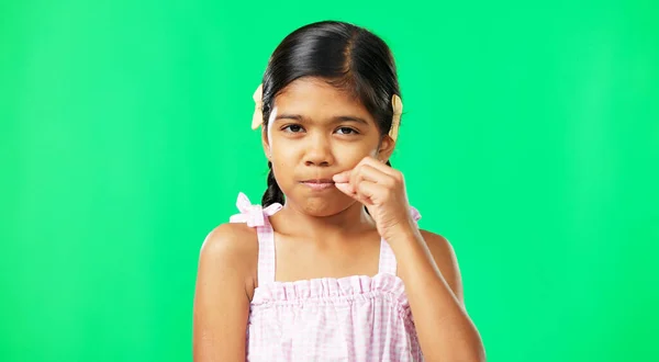 Children, secret and trust with a girl on a green screen background in studio zipping her lips. Portrait, kids and silent with an adorable little female child making a promise to keep quiet.