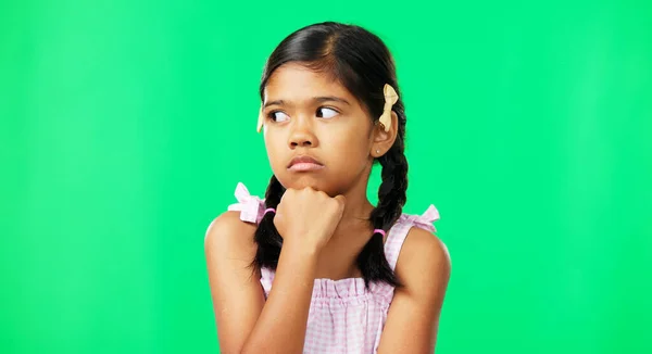 Kid, eye roll and annoyed girl with a green screen in a studio feeling bored while thinking. Think, young child and casual fashion of a student waiting, tired and isolated with youth while frustrated.