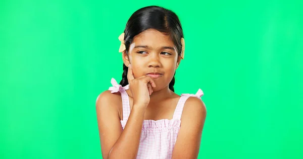 Thinking, green screen and idea by child with a question feeling excited, thoughtful and isolated in studio background. Planning, girl and joyful kid is happy, curious and planning expression.