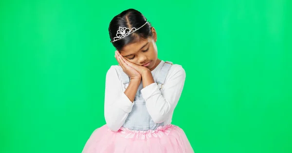 Sleeping, tired gesture and child on green screen with crown, princess costume and tutu in studio. Sadness, sleepy mockup and isolated young girl with fatigued, dreaming and nap expression for rest.