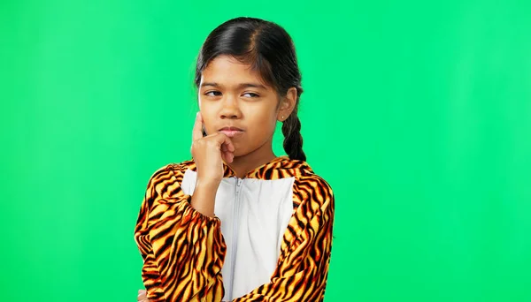 Child, girl and thinking of idea on green screen background with mockup space for plan or choice. Indian kid portrait in studio with hand on chin to think, planning or brainstoming decision.