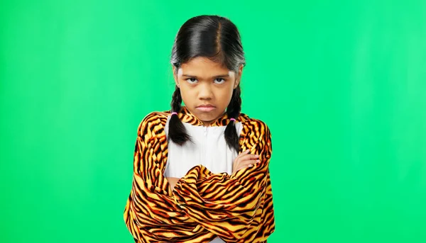 Girl child, angry face and green screen studio with arms crossed, refuse or shake head in tiger pyjamas. Frustrated kid, anger or portrait for mock up with mad, tired or bored expression by backdrop.