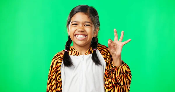 Children, perfect and hand gesture with a girl on a green screen background in studio feeling good. Portrait, smile and emoji with an adorable happy female child on chromakey mockup looking positive.