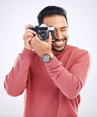 Fotoğraf, mutlu ve stüdyoda fotoğraf makinesi olan bir adam yaratıcılık ya da sanat fotoshoot işi için. Mutluluk, gülümseme ve Hintli erkek fotoğrafçı paparazzi ya da medya için beyaz arka planda fotoğraf çekiyor..