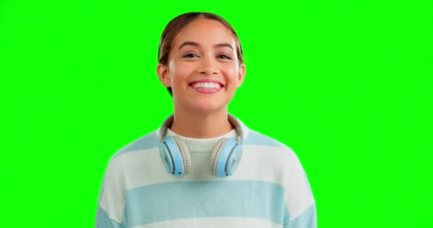 面白いと彼女の首の周りにヘッドフォンでスタジオで緑の画面の背景に女性 肖像画 笑顔とユーモア魅力的な若い女性と音楽を聴く上でChromakeyモックアップ — ストック動画