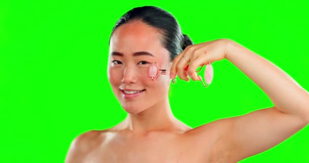 护肤的微笑和亚洲女人与滚筒在绿色屏幕上的背景隔离在工作室 健康面部肌肤按摩用玫瑰石英的肖像 皮肤科及快乐女性模型 — 图库视频影像