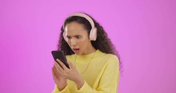 スタジオでの混乱 女性と電話はピンクの背景にすごい 悪いと失望した表現で 偽のニュース 噂やソーシャルメディア ドラマやポッドキャスト孤立のためのスマートフォンアプリ上の女の子による絵文字 — ストック動画