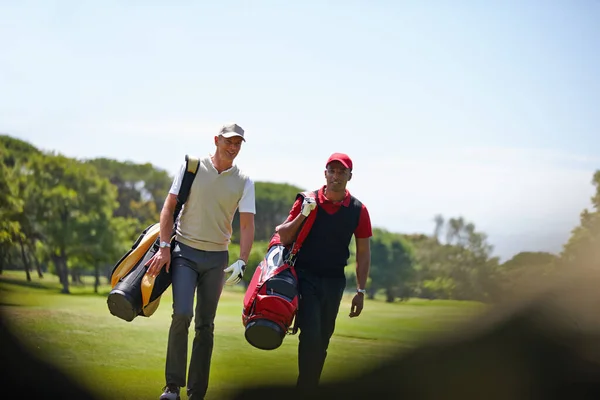 在回来的路上两个提着高尔夫球袋走过高尔夫球场的人 — 图库照片