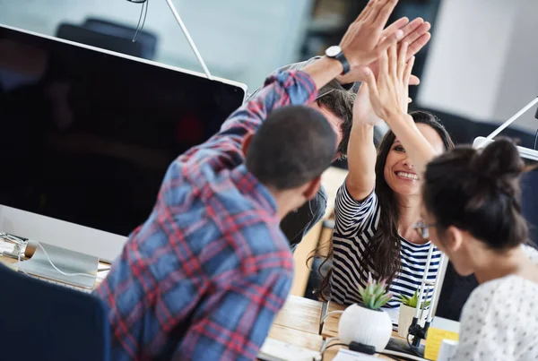 stock image Make creativity a job. a group of young office workers sitting at their computers and hi-fiving each other