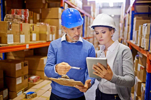 stock image Comparing order stats. a man and woman inspecting inventory in a large distribution warehouse