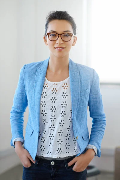 Ive got the will and means to succeed. Portrait of a focused young woman in glasses standing in an office