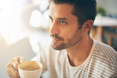 Kahve içerken düşüncelerini topluyor. Kafede kahve içen genç bir adamın yakın plan fotoğrafı.