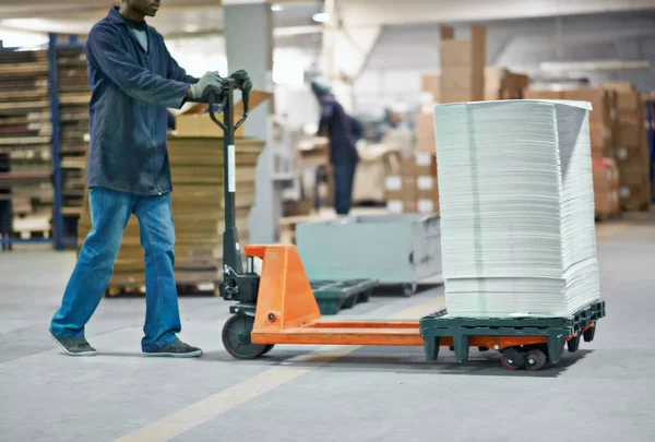 Getting the order out on time. Cropped image of a man moving a pile of paper in a factory