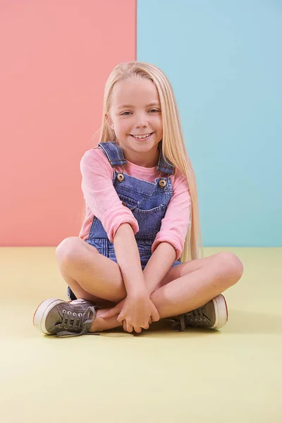 让你看到她最灿烂的笑容一个可爱的金发小女孩盘腿坐在演播室里 — 图库照片