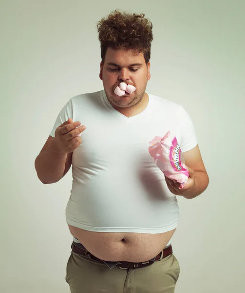 Im trying to eat light foods. an overweight man with marshmallows shoved in his mouth