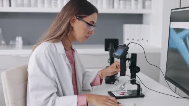 Pesquisa Microscópio Computador Com Uma Mulher Escrevendo Notas Enquanto Trabalhava — Vídeo de Stock