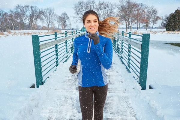 ランニングは私の好きな冬のアクティビティです 雪の中を走りながら暖かい服を着た女性が — ストック写真