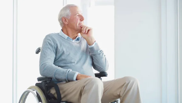 stock image So many moments lead to this. a senior man in a wheelchair looking thoughtfully out of a window