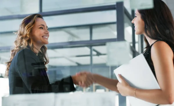 stock image Its a pleasure to finally meet you. Low angle shot of two attractive young businesswomen shaking hands while standing in their office