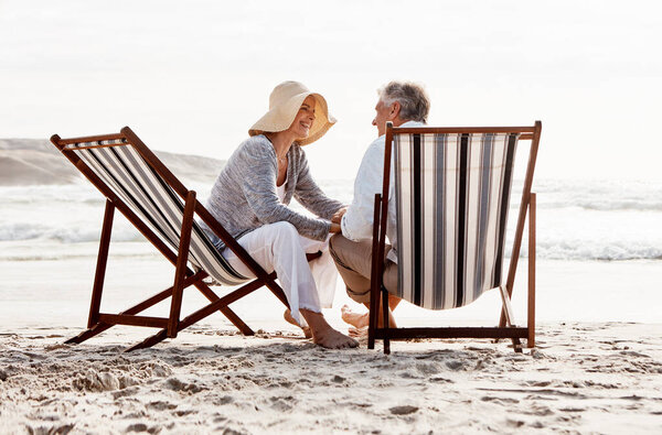 Falling even deeper in love. Full length shot of an affectionate middle aged couple relaxing on loungers at the beach