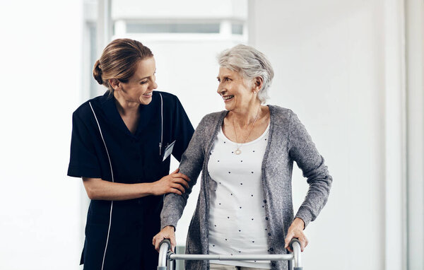 I couldnt have done it without your motivation. a female nurse assisting a senior woman using a walker
