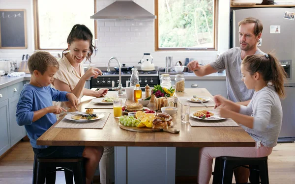 家庭时间是快乐的时光 两个充满爱心的年轻父母在家里的厨房里和孩子们一起吃早餐 — 图库照片