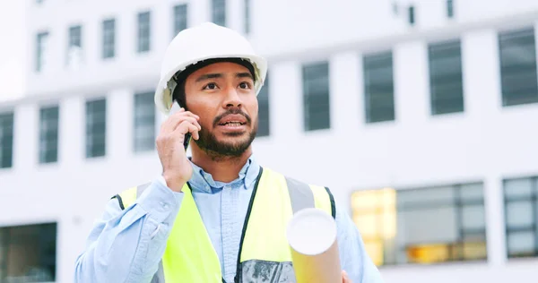 Civil engineer on a phone call while at a construction site discussing a strategy and plan to work on. Close up portrait of confident architect talking with building in the background and copy space.