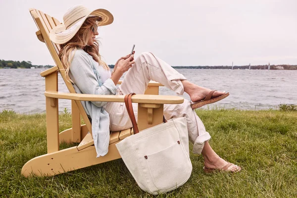 忘记飞行模式 让它处于放松模式 一个年轻貌美的女人在湖边用智能手机放松一下 — 图库照片