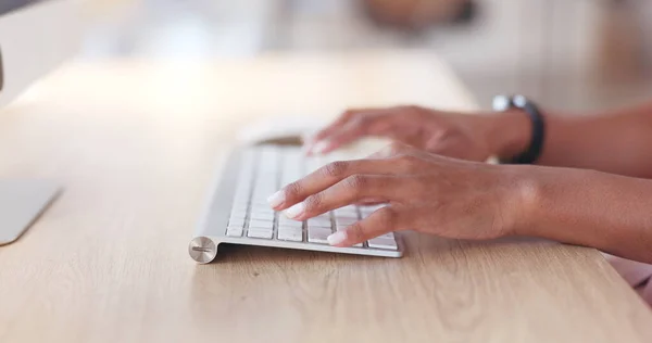 Closeup of a businesswoman browsing on a computer keyboard against a white background. Hands of a productive entrepreneur typing emails and compiling online reports while doing research and planning.