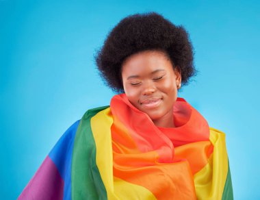 Gökkuşağı, mutlu ve siyah kadın stüdyoda eşcinsel topluluğu, eşcinsel hakları ve homoseksüel gururu için lgbtq bayrağı taşıyor. Mavi arka planda lezbiyen, biseksüel ve trans desteğe sahip bir kızın bedava gülümsemesi ve yüzü.