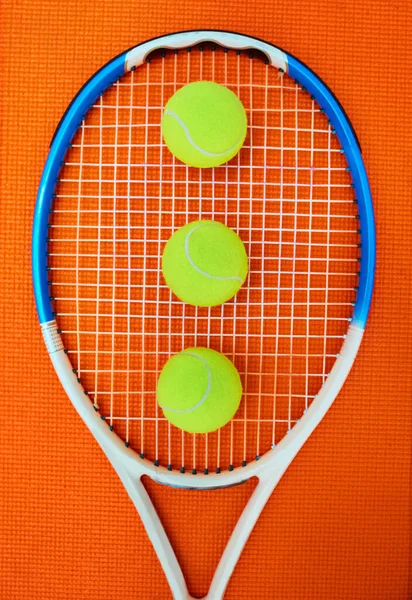 彼らは私の友人だ スタジオ内のオレンジの背景に置かれた1つのテニスラケットといくつかのテニスボールの高角度ショット — ストック写真